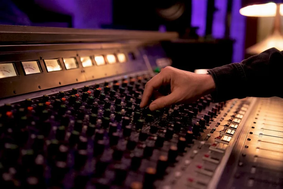 Hand adjusting audio mixer knobs at first listen