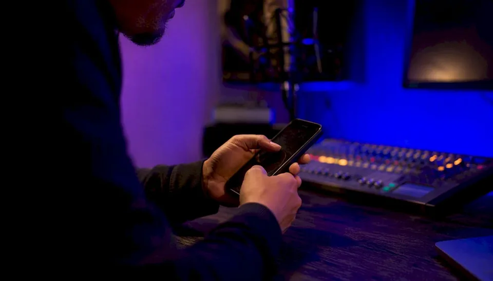 Musician's hands scrolling phone in studio