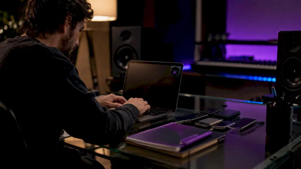 Hands editing audio metadata on laptop at studio desk