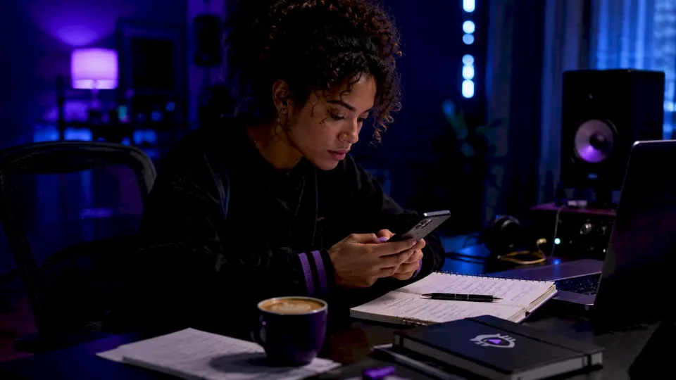 Hands scrolling playlist analytics at café table